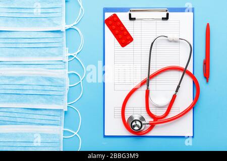 Appuntamento medico. Stetoscopio rosso, maschere igieniche mediche, compresse, documenti medici sul posto di lavoro dei medici in clinica. Concetto di medicina sanitaria Foto Stock