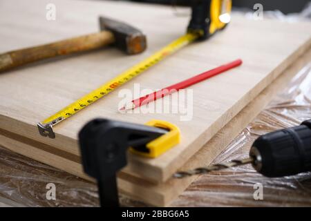 Gli utensili per carpentiere e la trivella si trovano su una tavola di legno Foto Stock