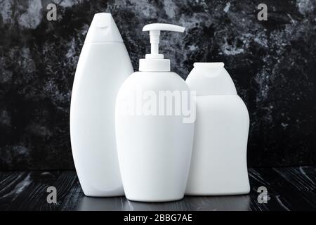 Bottiglie di plastica bianca di shampoo, sapone liquido antibatterico e gel doccia su sfondo di marmo nero in bagno. Concetto di igiene, disinfezione. P Foto Stock