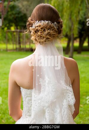 questo è un esempio di foto di capelli stile per spose. ci sono un sacco di cerchi sui capelli biondi. sposa è già indossare il suo abito e stare in piedi su un parco Foto Stock