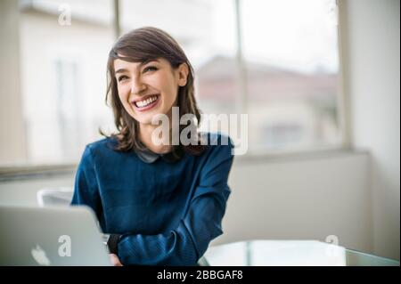 Ritratto di una giovane donna d'affari sorridente che usa un computer portatile Foto Stock