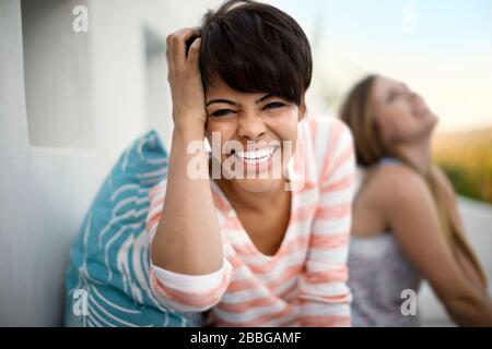 Ritratto di donna sorridente con un amico seduto sullo sfondo Foto Stock