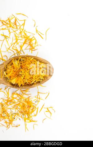 DriedCalendula officinalis, il marigold del POT, le rudddles, il marigold comune o marigold dello Scotch fiorisce su cucchiaio di legno su sfondo bianco. Vista dall'alto. Foto Stock