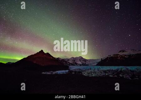 Aurora danza ovale su moutains e ghiacciaio in Islanda Foto Stock