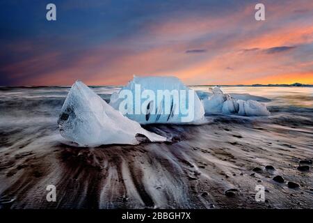 Tramonto su spiaggia di sabbia nera con ghiacciai in Islanda (immagine composita) Foto Stock