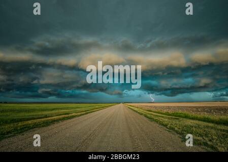 Tempesta con shelf cloud e fulmine su strada rurale ghiaia in Saskatechewan Canada Foto Stock