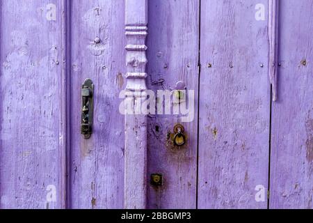 e' una vecchia porta viola di legno in un villaggio. C'è una vecchia maniglia in ferro sulla porta viola Foto Stock