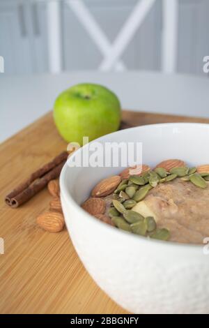 Colazione salutare: Porridge farinata d'avena con cannella, mela e banana con mandorle e semi di zucca cosparsi sulla parte superiore Foto Stock