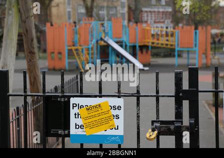 Un parco giochi per bambini rinchiuso e abbandonato nel sud di Londra, nel Regno Unito, durante lo scoppio del virus Corona del 2020. Cancelli bloccati con lucchetto, segnale di avvertimento sul cancello. Foto Stock