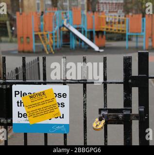 Un parco giochi per bambini rinchiuso e abbandonato nel sud di Londra, nel Regno Unito, durante lo scoppio del virus Corona del 2020. Cancelli bloccati con lucchetto, segnale di avvertimento sul cancello. Foto Stock