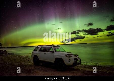 Aurora danza sulla spiaggia e l'acqua nel lago Winnipeg, Manitoba, Canada Self ritratto con la mia toyota 4runner come primo piano godendo lo spettacolo. Foto Stock