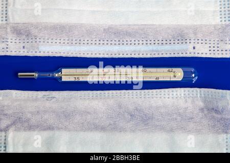 maschere mediche e termometro su sfondo blu Foto Stock