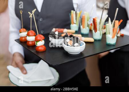 Piccoli spuntini adagiati su un vassoio. Il cameriere può contenere un vassoio di appetitosi spuntini Foto Stock