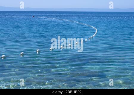 Linea di boe bianche di sicurezza in mare blu. Vista orizzontale. Spazio di copia. Foto Stock