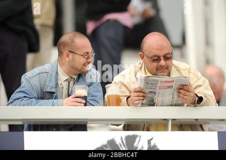 Racegoers goditi l'azione all'ippodromo di Epsom Downs Foto Stock