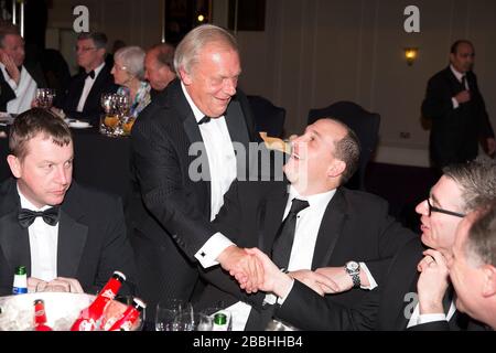 Il Chief Executive di PFA Gordon Taylor OBE saluta gli ospiti a un tavolo durante i PFA Player of the Year Awards 2013 al Grosvenor House Hotel di Londra. Foto Stock