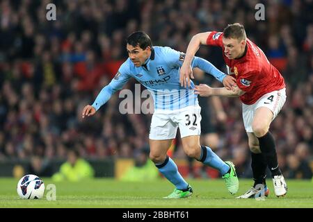 Carlos Tevez (a sinistra) e Phil Jones (a destra) del Manchester City si scontrano per la palla Foto Stock