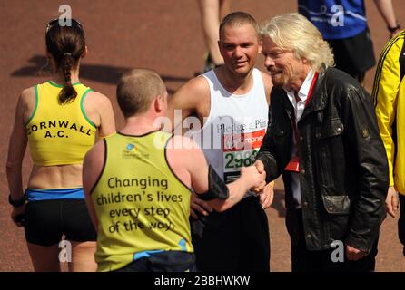 Sir Richard Branson si congratula con i corridori durante la Virgin London Marathon di Londra Foto Stock