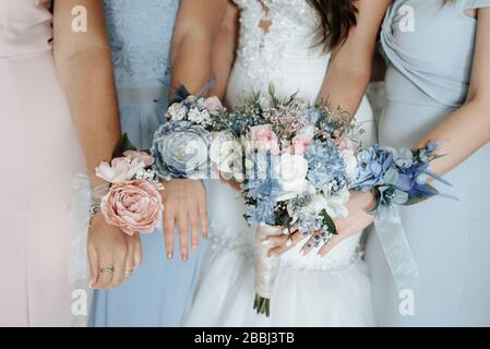 Sposa e bridesmaids mano con bei fiori. I bridesmaids hanno controllo sui bouquet Foto Stock