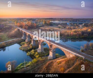 Vista aerea del ponte ferroviario e del fiume al tramonto in autunno Foto Stock