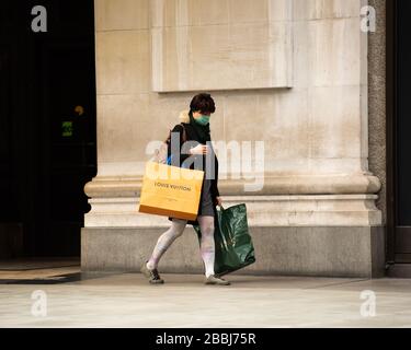 Una donna che indossa la maschera facciale, shopping a Londra, Inghilterra durante il blocco del virus corona. Foto Stock