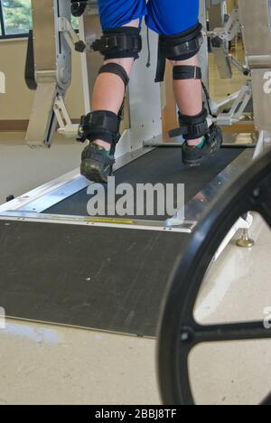 Vista parziale di un uomo in terapia fisica su una macchina che aiuta le gambe paralizzate a camminare Foto Stock