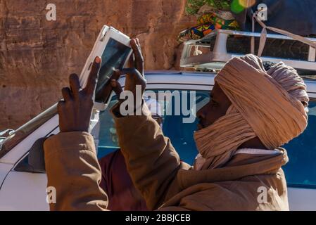 Tibesti, Ciad - 31/12/2012. Giovane uomo locale del Ciad sta facendo una foto utilizzando un tablet. Foto Stock