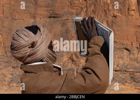 Tibesti, Ciad - 31/12/2012. Giovane uomo locale del Ciad sta facendo una foto utilizzando un tablet. Sullo sfondo formazioni rocciose di Tibesti. Foto Stock