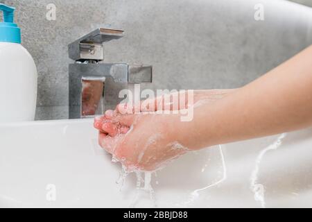 Bracci di lavaggio femminili da microbi e virus durante la pandemia mondiale di coronavirus a casa bagno lavello con gel di pulizia Foto Stock