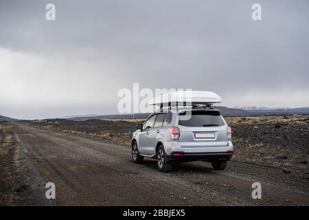 Auto che guida su strada di ghiaia in Islanda Foto Stock