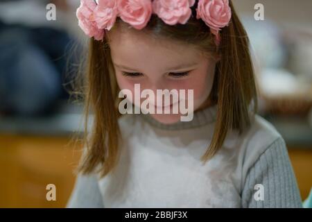 Ragazza con un cerchietto rosso fiore guarda verso il basso sorridendo Foto Stock