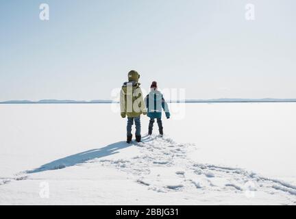 I bambini camminano attraverso un lago ghiacciato in Svezia Foto Stock