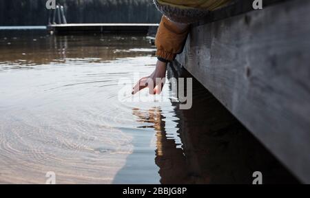 La mano del bambino che si fa un'acqua di mare sulla spiaggia in Svezia
