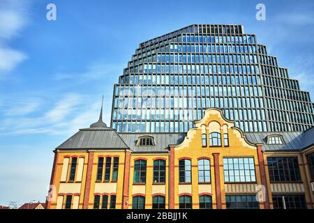 Un edificio storico di una ex casa di stampa e la facciata di un moderno edificio di uffici a Poznan Foto Stock