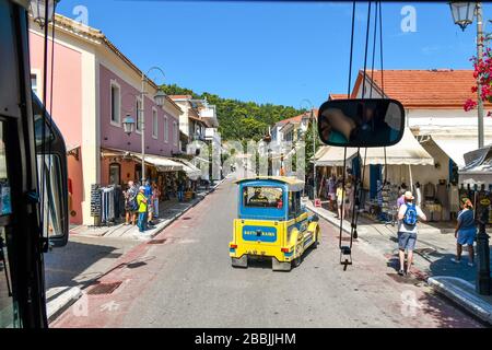 Un autobus turistico segue un treno turistico mentre guida attraverso il piccolo villaggio costiero di Katakolon, Grecia, sito del porto delle navi da crociera di Olympia. Foto Stock