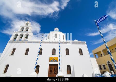 La Chiesa di Panagia Platsani con una bandiera greca che vola nel villaggio collinare di Oia, sull'isola di Santorini, Grecia. Foto Stock