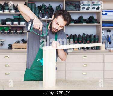 Carpenter trapani un foro con un trapano elettrico Foto Stock