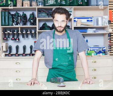 Il falegname si posa in un'officina polverosa Foto Stock