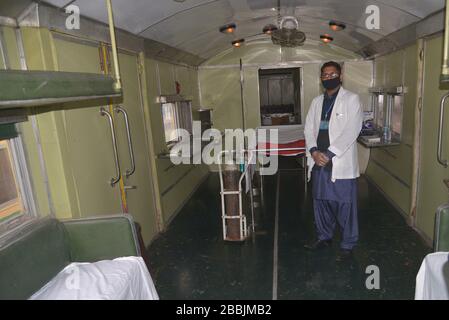 I membri del personale medico pakistano indossano la maschera facciale mentre installano il poster su un treno d'affari che ha preparato come un impianto di quarantena temporanea alla stazione ferroviaria sull'istruzione del ministro federale per la ferrovia mentre il blocco nazionale imposto dal governo come misura preventiva contro il (COVID-19) coronavirus a Lahore. Il numero di morti nel paese da COVID-19 sale a 26'. Il numero di casi confermati di COVID-19 in Pakistan è salito a 1.987 di martedì, dopo che sono stati segnalati nuovi casi nel paese. Il numero totale dei casi confermati di lunedì era di 1.987 casi su cui Sindh ha segnalato 676 casi, Foto Stock