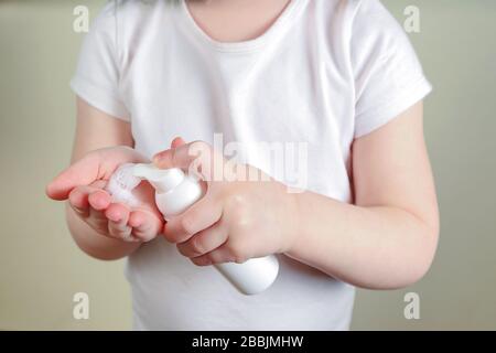 Bambino che applica la schiuma igienizzante sulle sue mani. Foto Stock