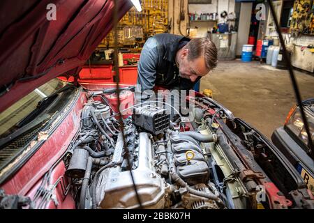 Berlino, Germania. 31st Mar, 2020. Andreas Lemmer, meccanico e proprietario della sua officina, sta lavorando su un'auto. Credit: Fabian Sommer/dpa/Alamy Live News Foto Stock