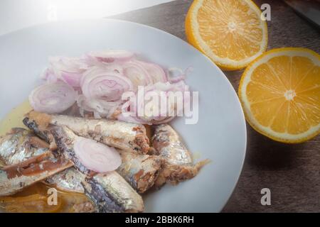 studio foto di sardinas con due limoni tagliati su una lastra bianca dalla composizione superiore su sfondo di legno Foto Stock