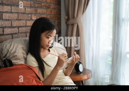 ragazza asiatica che studia mentre si rilassa in camera da letto Foto Stock