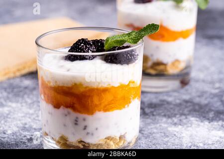 Dessert leggero e sano con yogurt, muesli, semi di Chia in yogurt, bacche e menta in bicchieri. Foto Stock