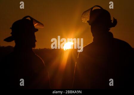 Stoccarda, Germania. 01st Apr, 2020. Due vigili del fuoco sono in piedi di fronte al sole dopo una missione, che sorge sopra la cappella funeraria sul Württemberg. Credito: Sebastian Gollnow/dpa/Alamy Live News Foto Stock