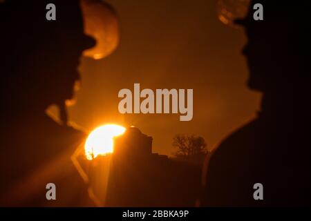 Stoccarda, Germania. 01st Apr, 2020. Due vigili del fuoco sono in piedi di fronte al sole dopo una missione, che sorge sopra la cappella funeraria sul Württemberg. Credito: Sebastian Gollnow/dpa/Alamy Live News Foto Stock