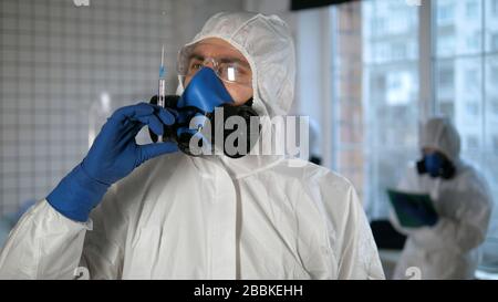 Vaccino Covid-19. Medico in un dispositivo di protezione che prepara la siringa per l'iniezione. Foto Stock