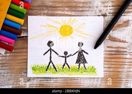 Famiglia di disegno della mano del bambino - Madre, Padre e Figlio con i pastelli della cera sullo sfondo di legno. Foto Stock