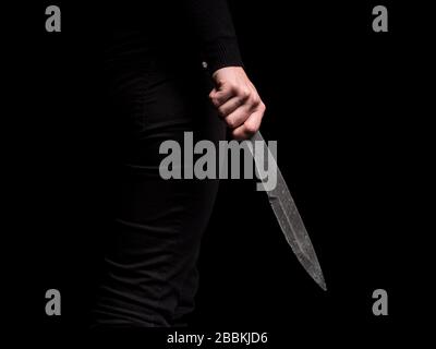 Ragazza che tiene in mano acciaio lancio coltello su sfondo nero Foto Stock