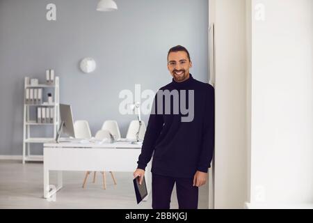 Uomo adulto positivo con tablet in mano in ufficio Foto Stock